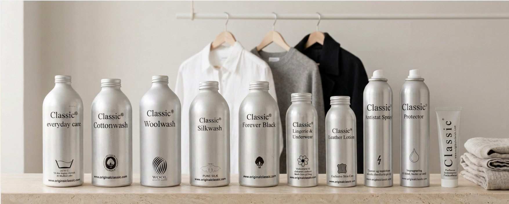 Hele Classic Clothing Care serien opstillet på en stenhylde foran skjorte, strik og frakke på bøjler